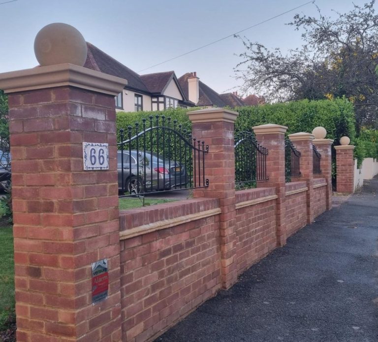 Front Brickwork Wall Brick wall with pillars and a gate, lined along a paved pathway in a residential area.